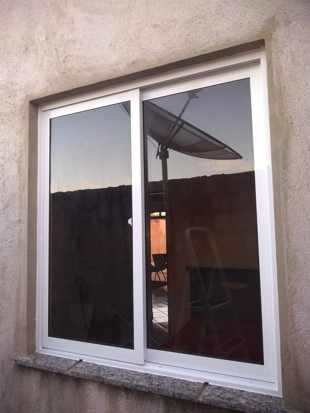 Janela de correr de alumínio branco com vidro reflexivo instalada em fachada